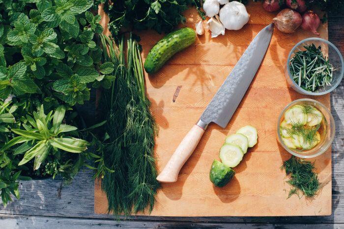 Japanese knife on cutting board surrounded by green vegetables